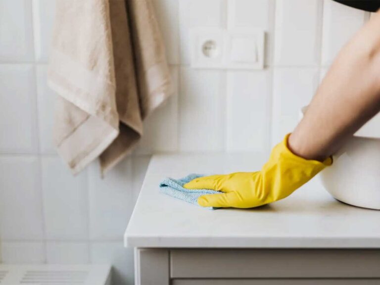person wearing a yellow glove using a blue cloth to perform professional house cleaning