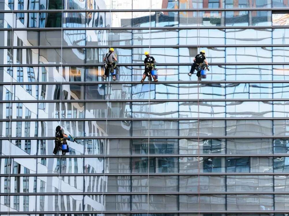 several workers hanging on a building performing professional window and glass cleaning in melbourne