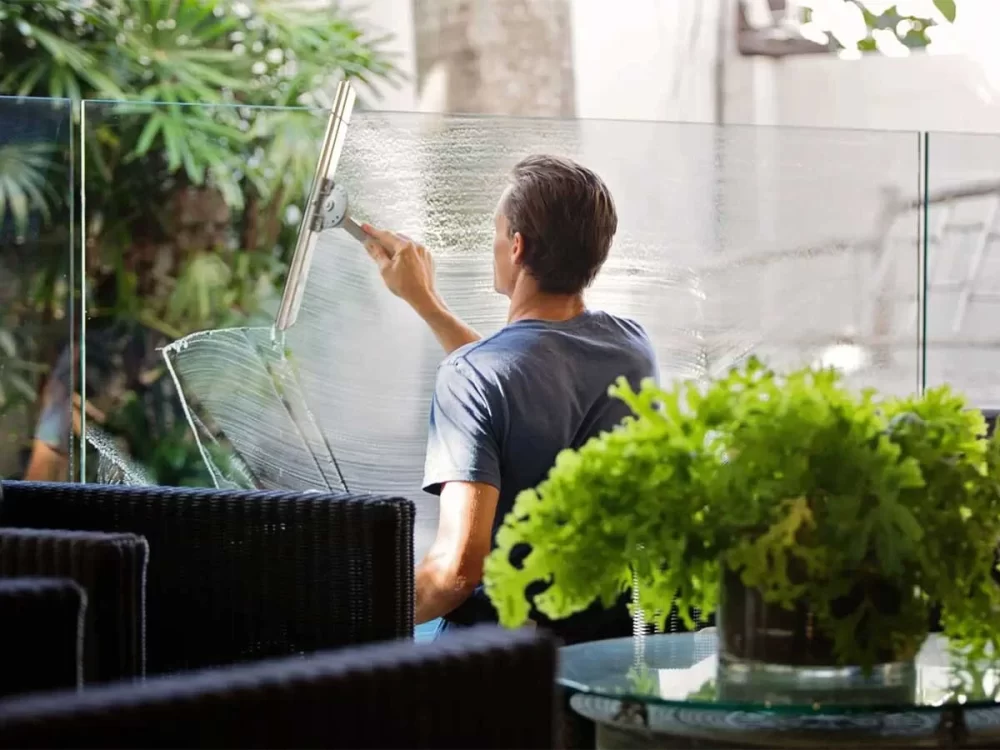 Man performing professional window cleaning on interior office glass window, ensuring a clear and spotless finish.
