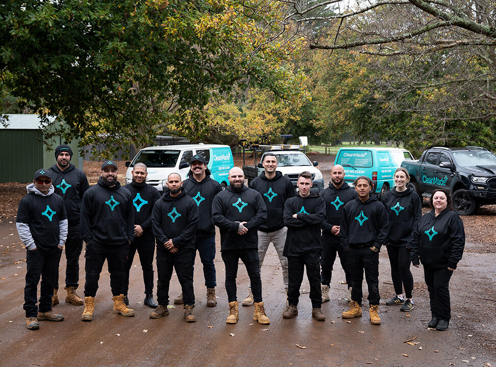 cleanmade staff standing in front of their parked company vehicles on a gravel carpark in a park