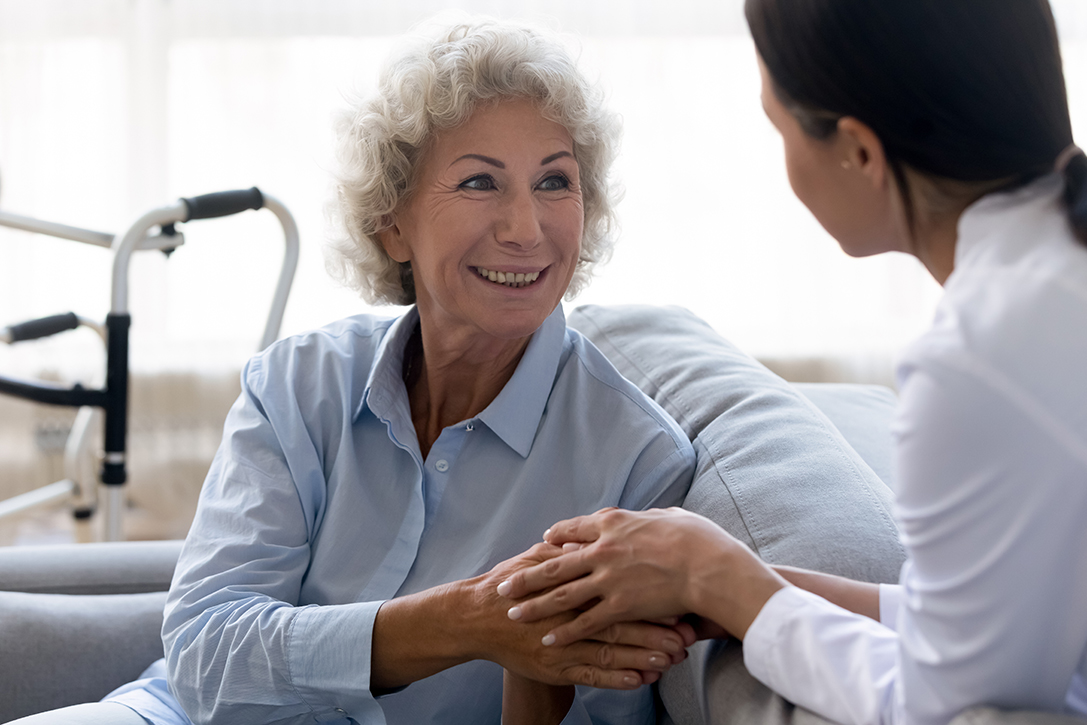 aged care facility cleaning with a smiling woman's hands being touched supportivly and comfortingly by a worker