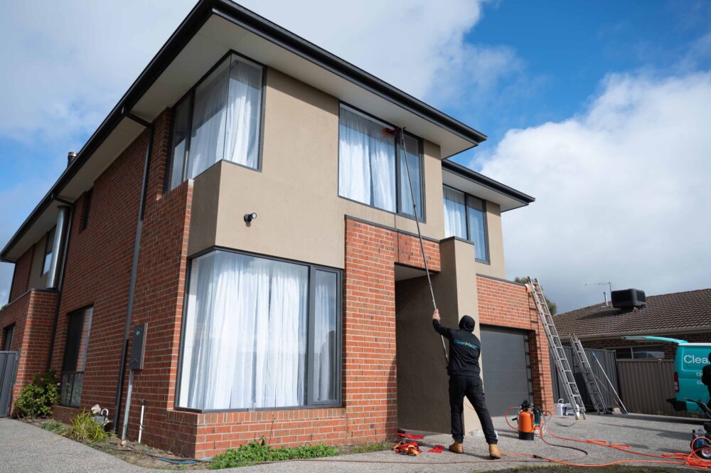 cleanmade technician using a long pole with a soft brush to perform window cleaning on a double-storey home in melbourne