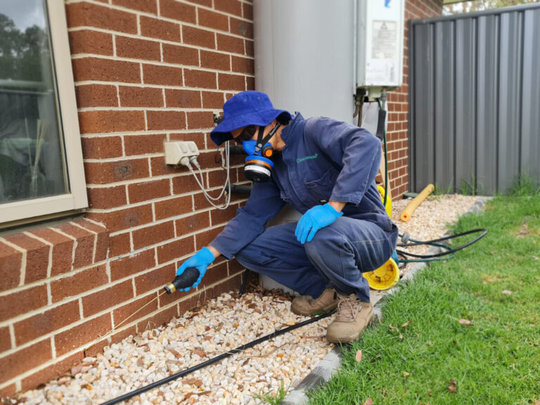 CleanMade pest controller technician spraying along the external perimeter of a brick home in Melbourne
