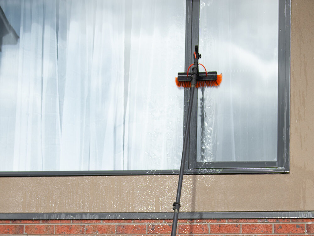 using a long pole and soft brush for window cleaning of a second-storey window in melbourne